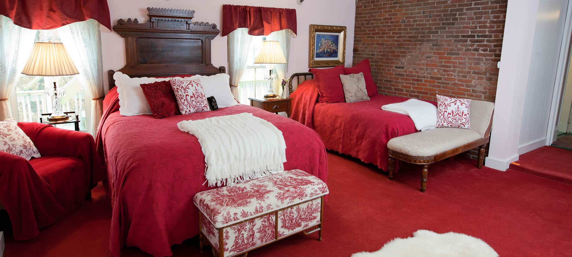 Prince Alfred guest room with red carpet, curtains and bedding, two beds and two windows
