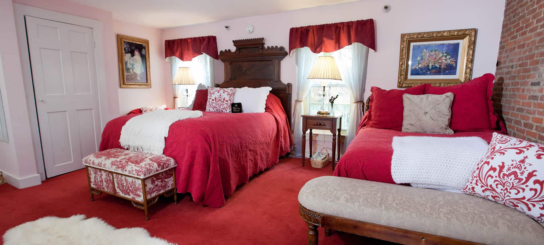 Prince Alfred guest room with two windows, two beds with red bedding and red carpet