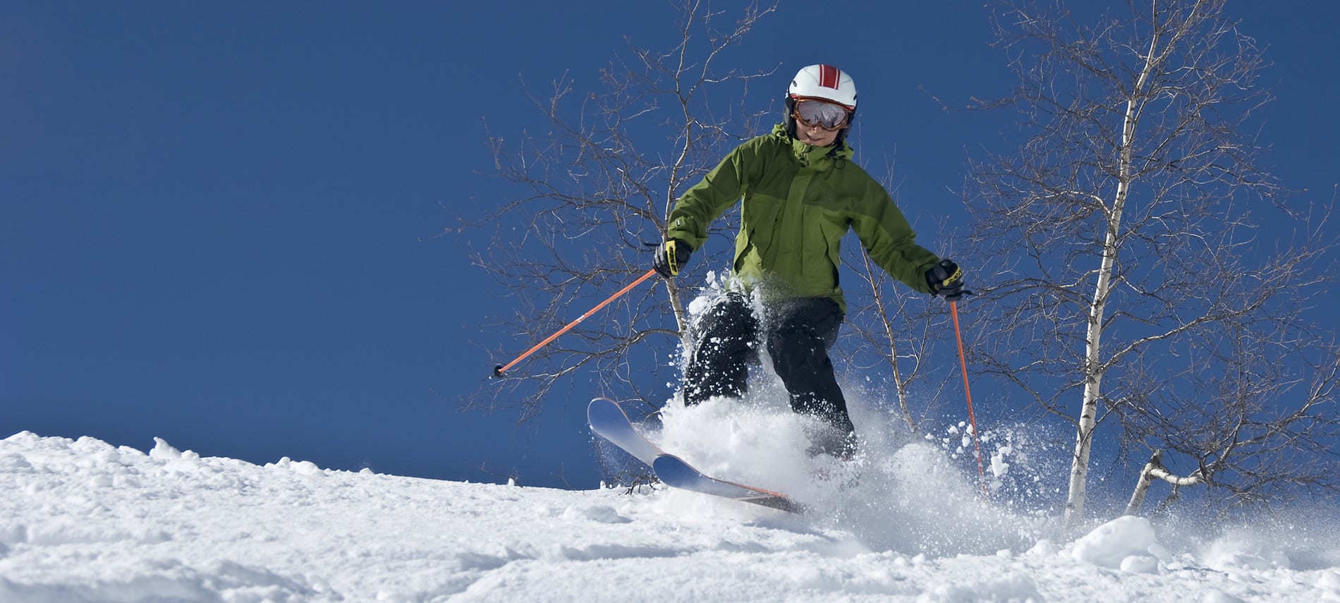Person snow skiing down hill amidst crisp blue skies