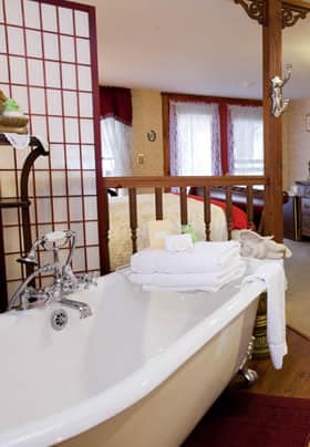 Princess Helena guest room with clawfoot tub behind white and wood room divider